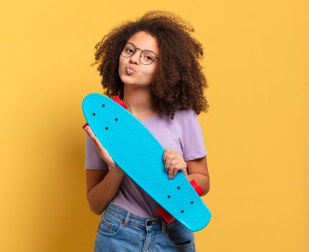 Pretty afro teenager girl with a skate board