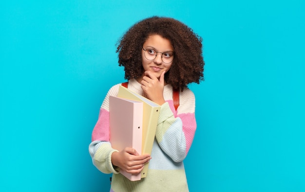 Photo pretty afro teenager smiling with a happy, confident expression with hand on chin, wondering and looking to the side. student concept