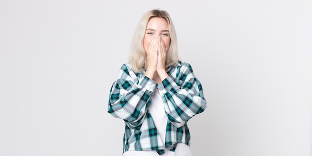 pretty albino woman looking happy, cheerful, lucky and surprised covering mouth with both hands