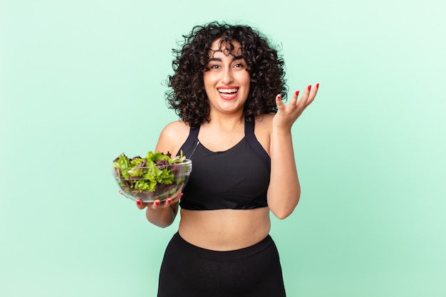 Pretty arab woman feeling happy, surprised realizing a solution or idea and holding a salad. diet concept