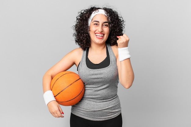 Pretty arab woman feeling shocked,laughing and celebrating success and holding a basketball ball. sport concept