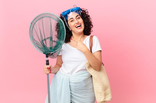 Pretty arab woman looking excited and surprised pointing to the side with goggles. fisher concept