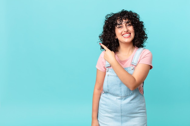 Pretty arab woman looking excited and surprised pointing to the side