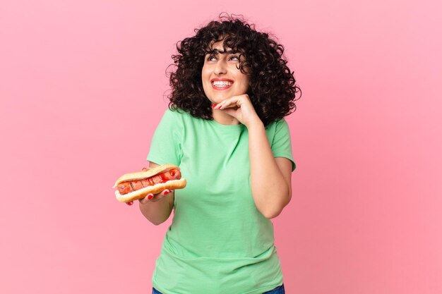 幸せに笑って、空想にふけるか、ホットドッグを疑って抱きしめるかなりアラブの女性