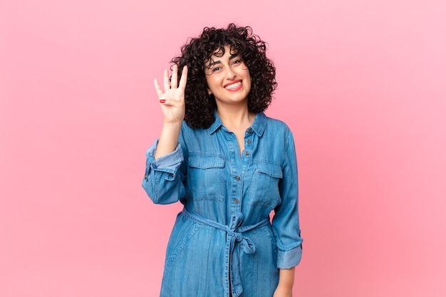 Pretty arab woman smiling and looking friendly, showing number four