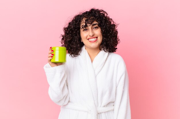 Pretty arab woman wearing bathrobe and holding a conditioner product