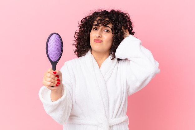 Pretty arab woman wearing bathrobe and holding a hairbrush