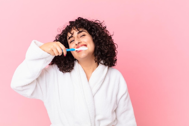 Foto bella donna araba che indossa accappatoio e usa uno spazzolino da denti