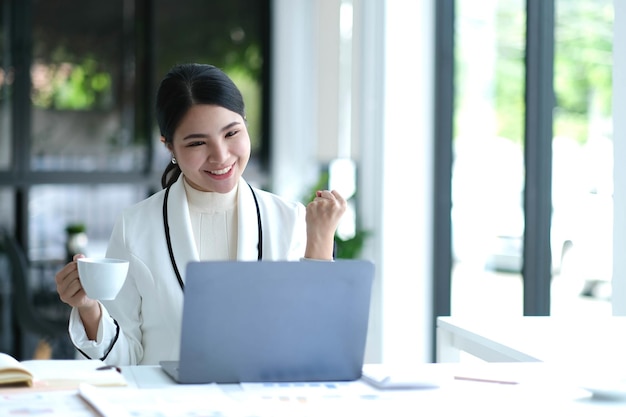 Pretty Asian businesswoman sitting on a laptop And the work came out successfully and the goal was achieved happy and satisfied with her