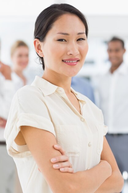 Pretty asian businesswoman standing with team behind her