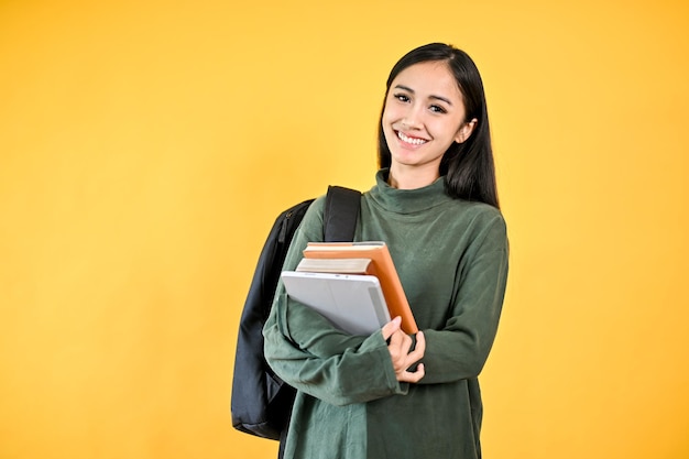 A pretty Asian female college student in a cozy sweater with her backpack holding her books