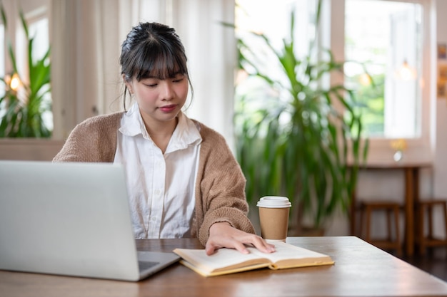 アジア系の可愛い女子大生がコーヒーショップのテーブルに座りながら仕事に集中している