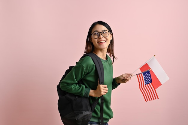 Pretty Asian female college student holding the flags of Poland and USA Exchange student