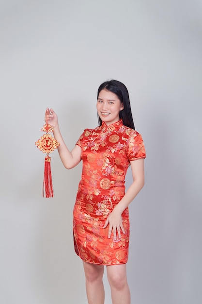 Pretty Asian girl with Chinese traditional dress cheongsam or qipao holding firecracker. Chinese new year concept, female model isolated in gray studio background