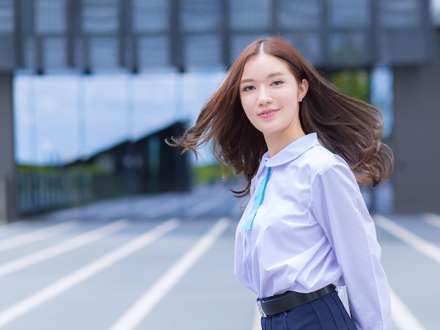 교정기가 달린 교복을 입은 예쁜 아시아 여고생이 자신 있게 돌아서고 있습니다.