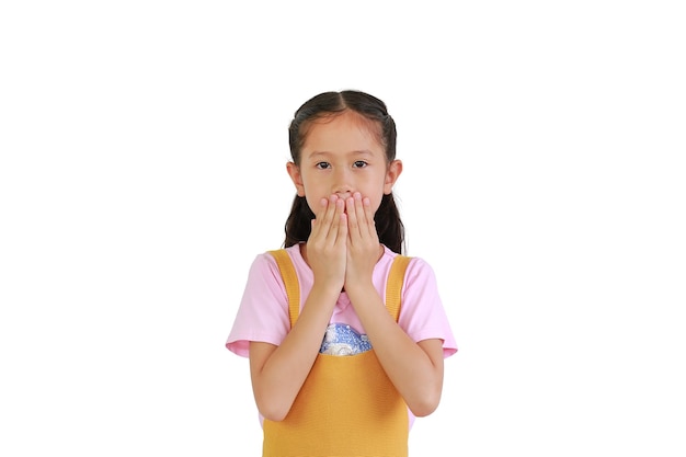 Довольно азиатская маленькая девочка, закрывающая рот руками, изолированными на белом фоне