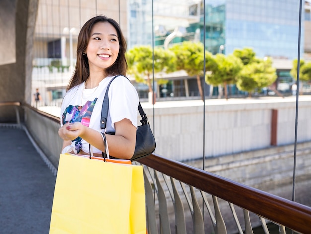 通りで買い物をするカジュアルな服装のかなりアジアの女性