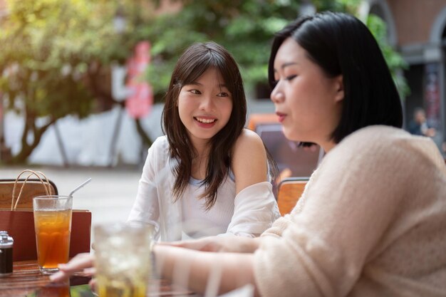 屋外カフェでくつろぎながら友人とおしゃべりを楽しむアジア系のかわいい女性