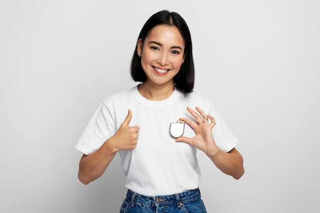 Pretty asian woman holding Implantable cardioverter defibrillator ICDs and showing cool gesture