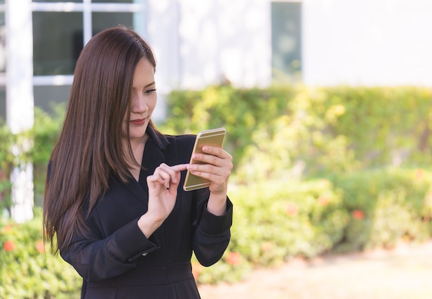 꽤 아시아 여자는 도시 공원에서 모바일 문자 메시지