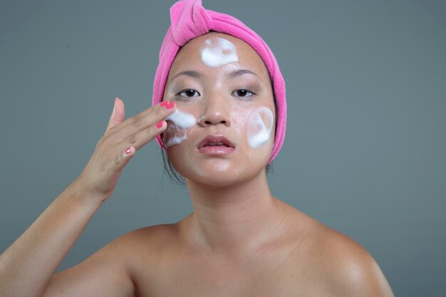 Pretty asian woman taking care of her skin isolated from the background beauty concept