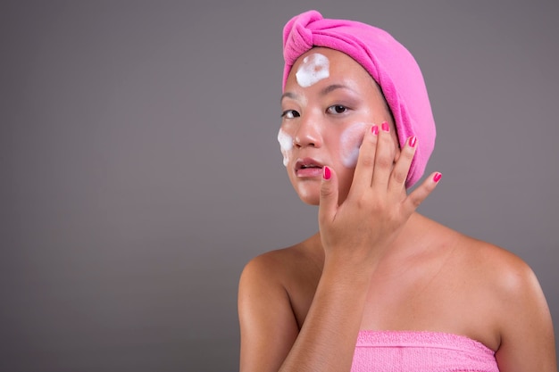 Pretty asian woman taking care of her skin isolated from the background beauty concept