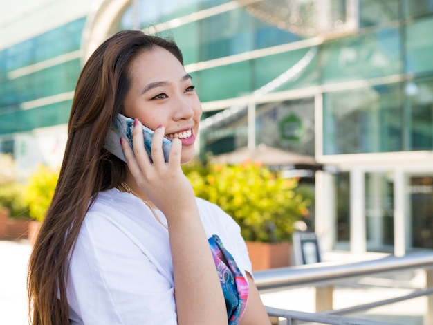 Pretty asian woman talking on the phone smiling