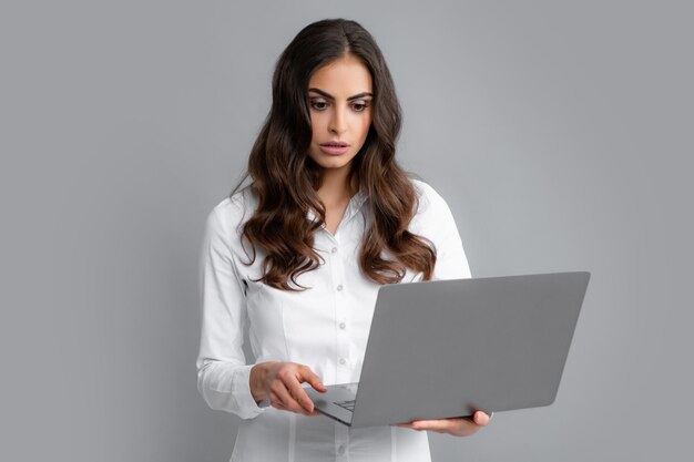 Pretty assistant holding notebook search information internet Young business woman with laptop computer isolated studio portrait on gray background Freelancer at work