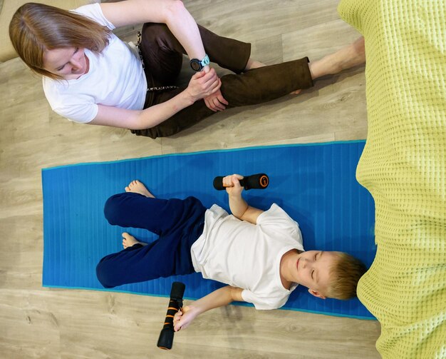 Pretty athletic mother and a young son play sports together at home healthy lifestyle