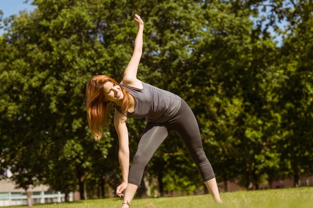 Pretty athletic redhead stretching in park