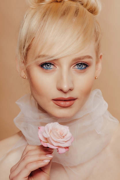 Pretty attractive girl with blond hair, fashion shooting, rose, simple background