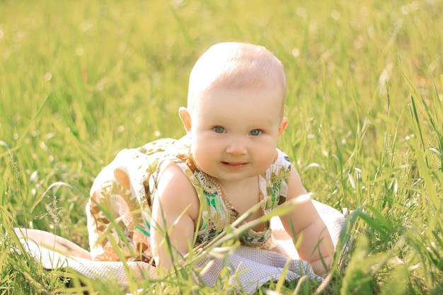 Pretty baby girl on the lawn in the spring day