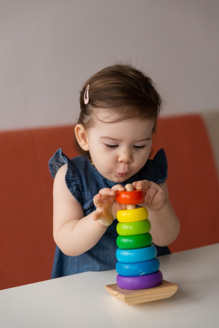 Pretty baby girl play with wooden colourful pyramid toy