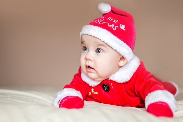 A pretty baby girl in a Santa Christmas costume is surprised by something