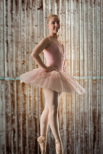 Pretty ballerina dancing against wooden planks