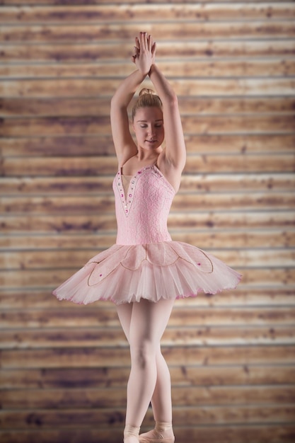 Pretty ballerina in pink against wooden planks