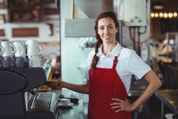 Pretty barista looking at camera and using the coffee machine