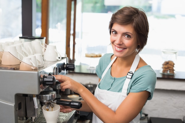 Pretty barista making coffee smiling at camera