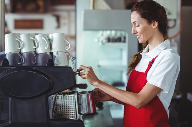 Pretty barista using the coffee machine 