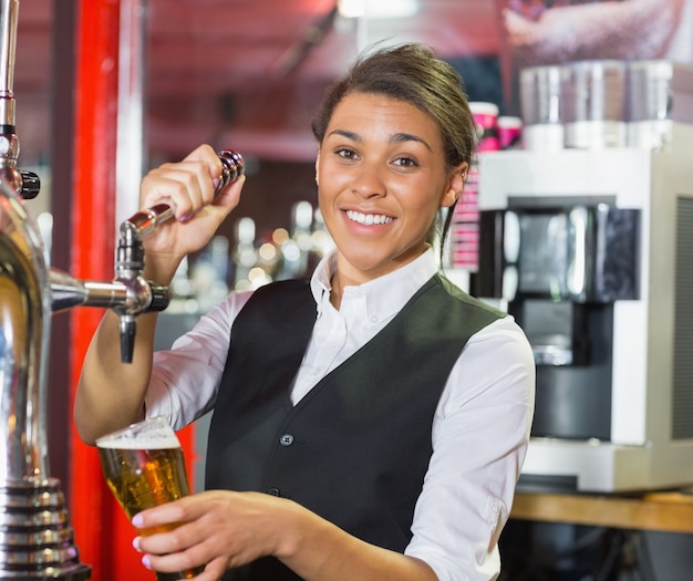 Foto bella cameriera tirando una pinta di birra