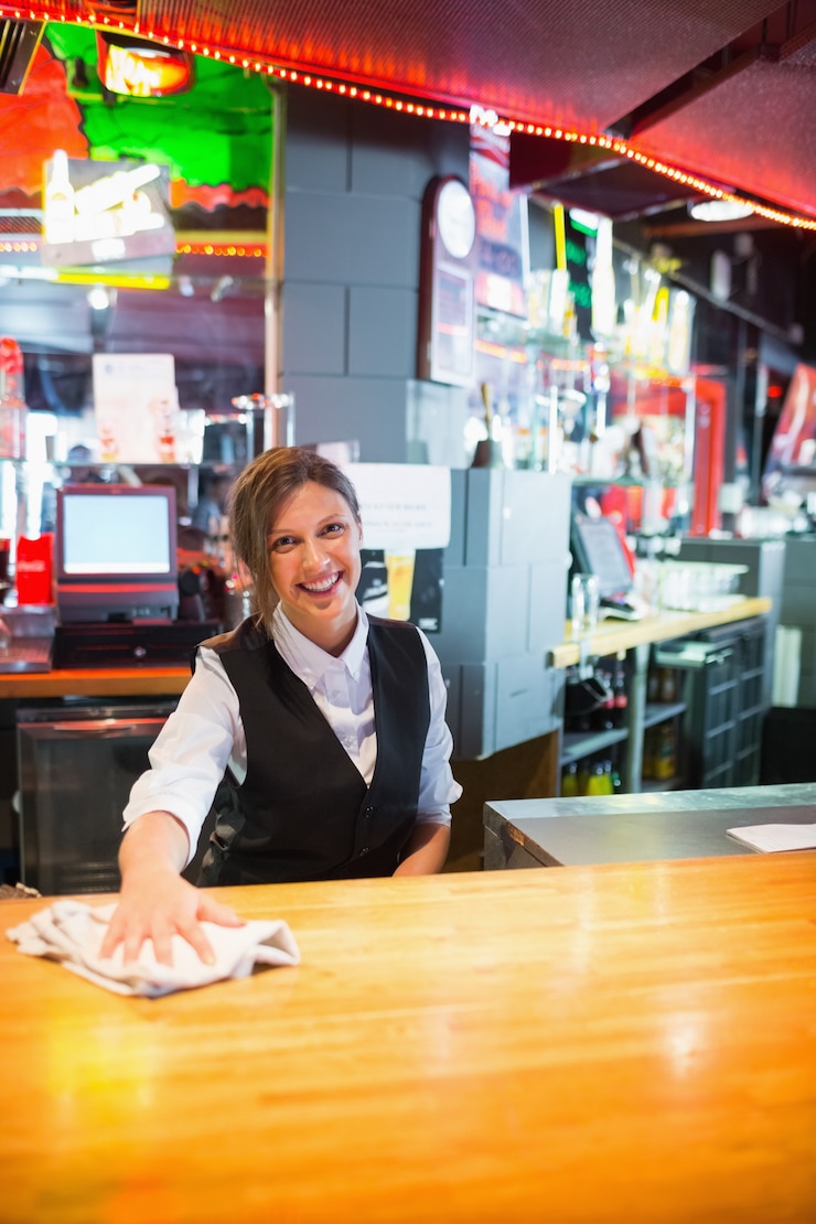 Photo pretty barmaid wiping down bar