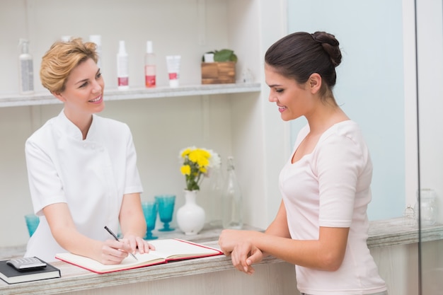 Pretty beautician talking with client