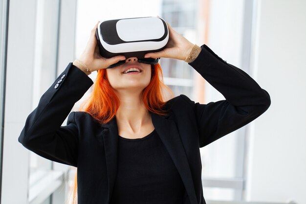 Pretty beautiful cute excited woman in VR headset trying to touch objects in virtual reality