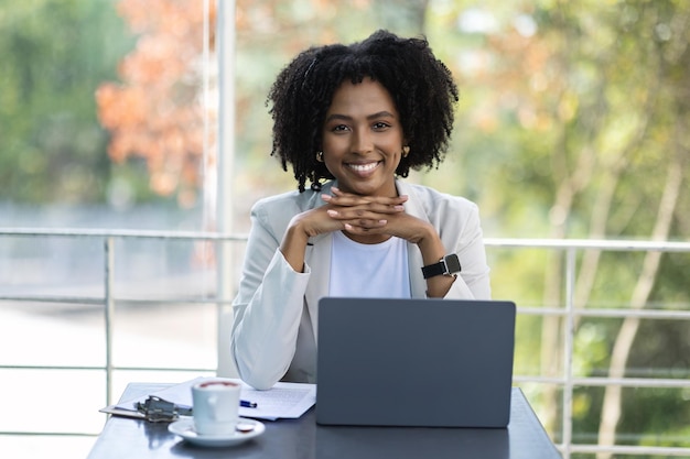 Pretty black lady businesswoman sitting at cafe using laptop