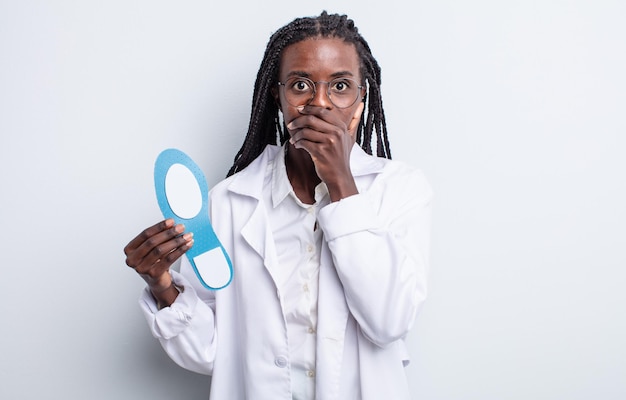 Pretty black woman covering mouth with hands with a shocked. podiatrist concept