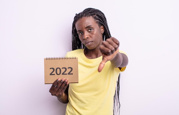 Pretty black woman feeling cross,showing thumbs down. 2022 calendar concept