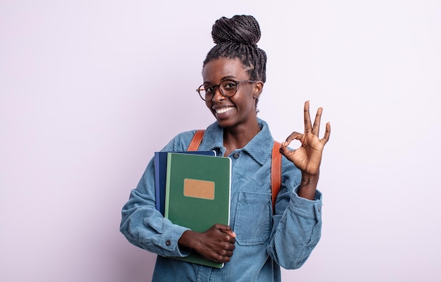 Bella donna di colore che si sente felice, mostrando approvazione con un gesto ok. studente con il concetto di libri