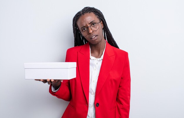 Pretty black woman feeling puzzled and confused. businesswoman with a white box