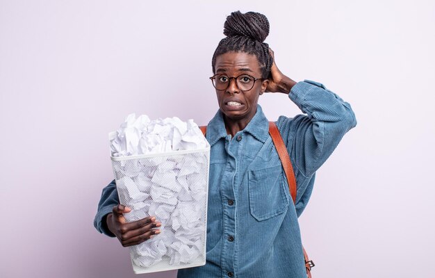 Pretty black woman feeling stressed, anxious or scared, with hands on head. paper balls failure concept