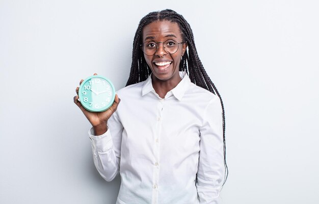 Pretty black woman looking happy and pleasantly surprised. alarm clock concept